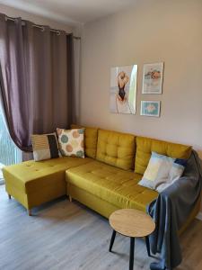 a living room with a yellow couch and a table at Apartamenty Poproszę na Plażę in Jastrzębia Góra