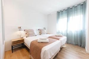 two beds in a white bedroom with a window at Bravissimo Falcó, 3 bedrooms and balcony in Girona