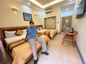 una donna seduta su un letto in una stanza d'albergo di Tuan Anh Cua Lo Hotel a Cửa Lô