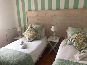 two beds in a bedroom with green and white stripes at Villa Amore in Paternoster