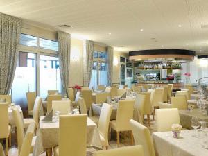 a dining room with white tables and chairs at Hotel Storione in Lido di Jesolo