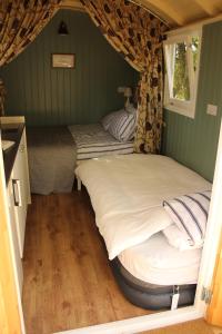 two beds in a small room with a window at The Kestrel Shepherd Hut, Whitehouse Farm in Stowmarket