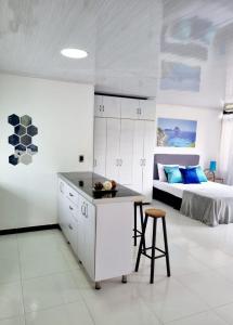 a white kitchen with a bed and a table and stool at Apartaestudio IBIZA 401 Edificio Europa Ibagué in Ibagué