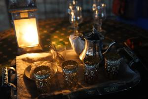 a table with a tray with glasses and a tea kettle at Merzouga Paradise Luxury Camp in Merzouga