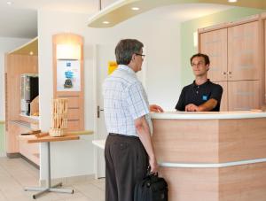 two men standing at a counter in a store at Ibis Budget Wuppertal Oberbarmen in Wuppertal