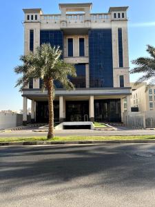 a building with a palm tree in front of it at Eliana Hotel in Al Khobar