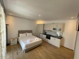 1 dormitorio con 1 cama blanca y cocina en Helen Apartments, en Lukovë