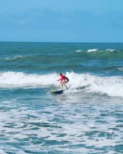 a person riding a wave on a surfboard in the ocean at HOSTAL Estrellas del tayrona playa in Santa Marta