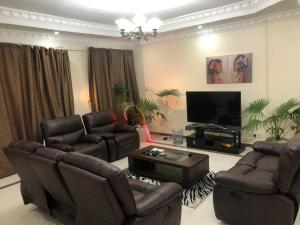 a living room with leather furniture and a flat screen tv at The Penthouse oysterbay in Dar es Salaam
