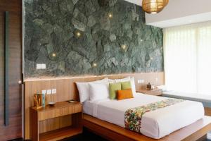 1 dormitorio con cama y pared de piedra en Zenubud, en Ubud