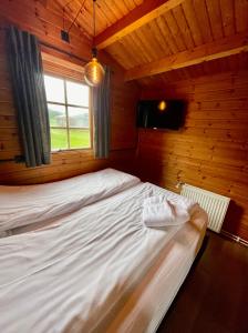a bed in a wooden room with a window at Ytri Vík in Hauganes