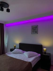 1 dormitorio con 1 cama con luces moradas en la pared en Residence SINAIA Apartments, en Sinaia