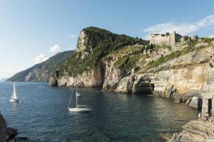 two boats in the water in front of a castle at Grand Hotel Portovenere in Portovenere