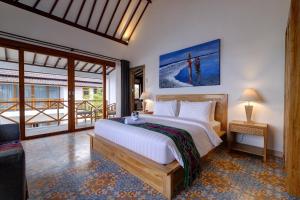 a bedroom with a large bed and a balcony at Wide Sands Beach Retreat in Pulukan