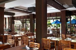 a restaurant with wooden tables and chairs and windows at Best Western Kuta Villa in Kuta
