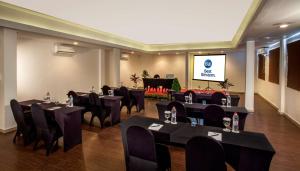 a conference room with black tables and chairs and a screen at Best Western Kuta Villa in Kuta
