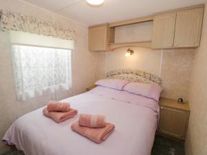 a bedroom with a bed with two towels on it at Fron Dderw Caravan in Holyhead