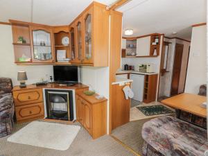 a living room with a kitchen with a stove at Fron Dderw Caravan in Holyhead