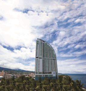 a tall building with palm trees in front of the ocean at Best Western The Lagoon Hotel in Manado