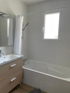 a bathroom with a white tub and a sink and a window at Maison neuve entre Bassin d'Arcachon et Landes in Le Muret +14 photos