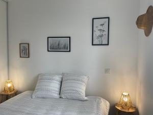 a white bed with three pictures on the wall at Maison neuve entre Bassin d'Arcachon et Landes in Le Muret