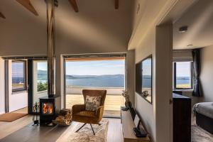 een kamer met een open haard en een slaapkamer met uitzicht op de oceaan bij Tidal Reach Dunhallin in Hallin