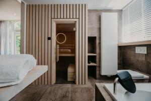 ein Bad mit einem Bett, einem Waschbecken und einem Spiegel in der Unterkunft Villa Westerduin in Renesse
