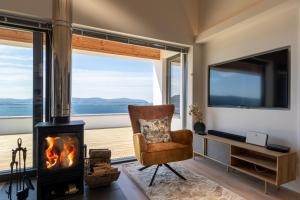 a living room with a fireplace and a tv and a chair at Tidal Reach Dunhallin in Hallin