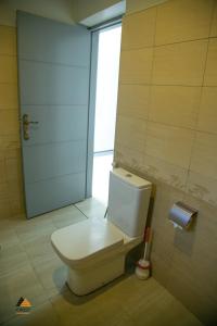 a white toilet in a bathroom with a door at CWEZI BY THE LAKE in Entebbe