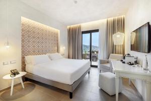 una camera con un grande letto bianco e una scrivania di Villa Fiorita Boutique Hotel a Taormina