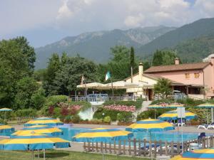 a resort with a pool with umbrellas and a fountain at Country House Cunial in Cavaso del Tomba