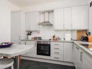 a white kitchen with white cabinets and a table at Stables Cottage in Langholm