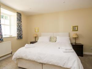 a bedroom with a large white bed and a window at Stables Cottage in Langholm