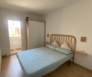 a bedroom with a bed with blue sheets and a window at Precioso apartamento en primera línea de mar in L'Escala