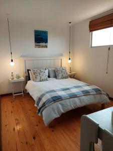 a bedroom with a large bed and two tables at Brandys beach house bettys bay in Bettyʼs Bay