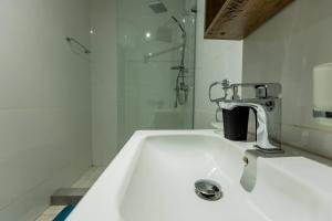 La salle de bains blanche est pourvue d'un lavabo et d'une douche. dans l'établissement Accra Fine Suites - Henrietta's Residences, à Accra