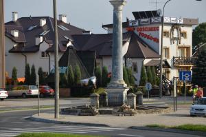 un monumento en medio de una calle con un edificio en Gościniec Podkowa, en Wlodawa