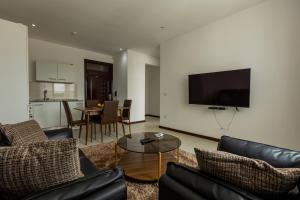 a living room with a couch and a tv on a wall at Accra Fine Suites - Henrietta's Residences in Accra