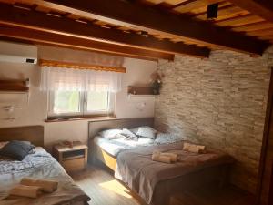 - une chambre avec 2 lits et un mur en briques dans l'établissement Gozdarjeva hiška M&K, à Dobrovnik