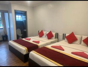 two beds in a room with red pillows on them at ESM Hotel in Tanah Rata