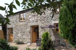a stone house with an umbrella in front of it at Tuell Farm Cottages in Tavistock
