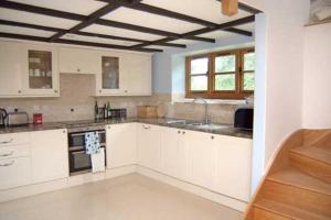 a large kitchen with white cabinets and a window at Tuell Farm Cottages in Tavistock