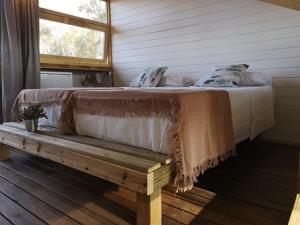 Cama en habitación con banco de madera en Camping Playa Taray, en Islantilla