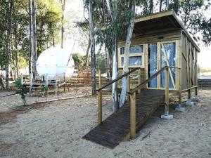 una pequeña cabaña de madera con un barco en el fondo en Camping Playa Taray, en Islantilla