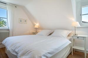 um quarto branco com uma cama branca e 2 janelas em Ferienhaus Immenstaad em Immenstaad am Bodensee