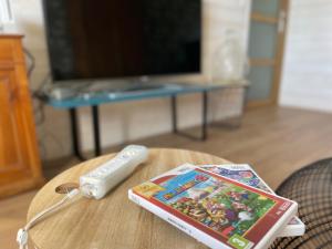 un contrôleur de jeu avec un wii et un livre sur une table dans l'établissement Maison familiale et cosy, à Roscanvel