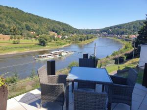 een tafel en stoelen op een balkon met uitzicht op een rivier bij Saechsische-Schweiz-Ferienhaus-Wohnung-2-mit-hervorragendem-Panoramablick-ueber-das-Elbtal in Königstein an der Elbe
