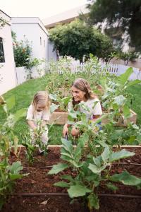 two girls are planting plants in a garden at Cretan Malia Park a Member of Design Hotels in Malia