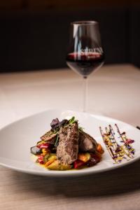 un plato con carne y verduras y una copa de vino en Hotel Bel Sit, en Valle di Cadore