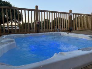 a hot tub on a deck with a wooden fence at Aladdin Safari Tent in Tenby